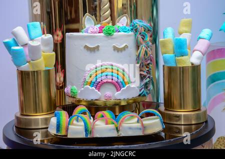 Geburtstagsfeier`s kleinen Mädchens; Desserttisch mit schöner Einhorn-Torte, Cake-Pops, Zuckerkeksen und Geburtstagsdekoration Stockfoto